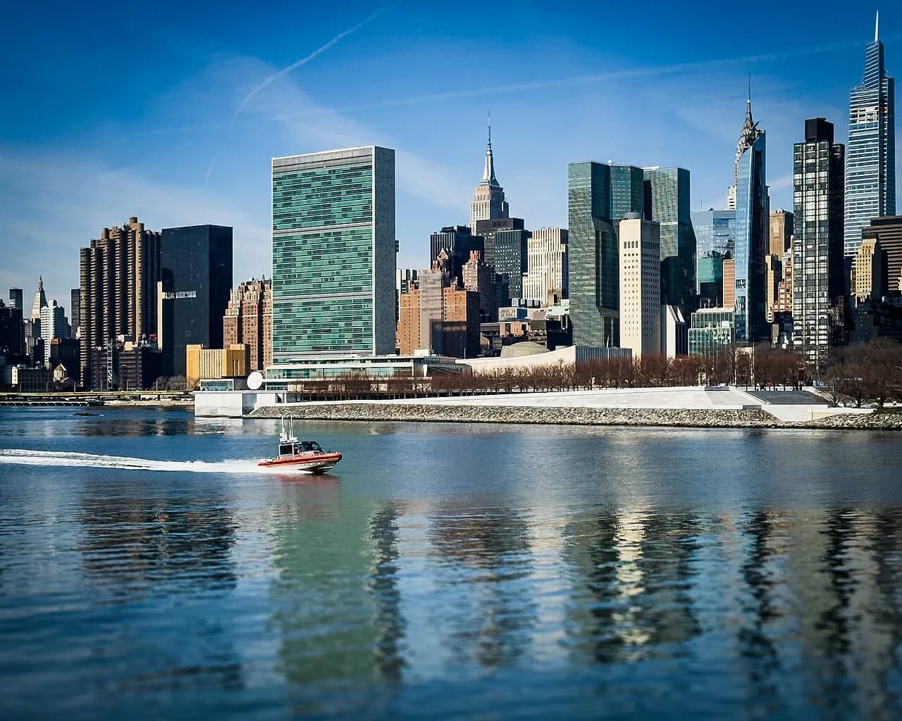 Boat passing United Nations Headquarters and surrounds, seen from the East River.jpg